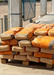 Pile of orange cement bags on a wooden pallet in an industrial setting.